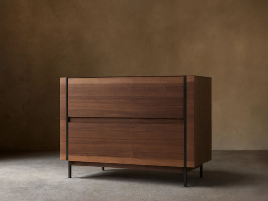 Mihaela Nightstand: A sleek walnut veneer nightstand with two hardware-free drawers, on dark metal legs, against a soft-toned wall.