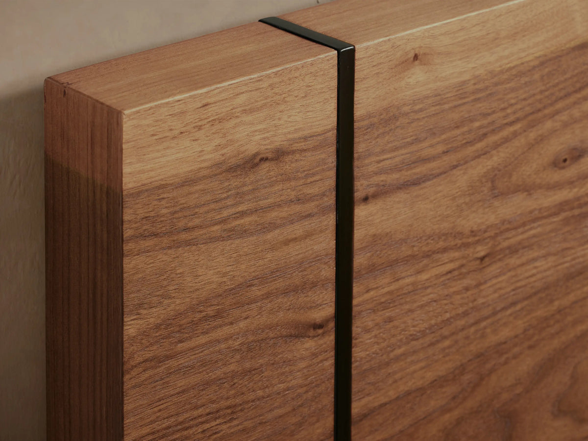 Mihaela Bed: Front view of a solid wood bed frame with rich brown oak grain, dark vertical accents, and white bedding.