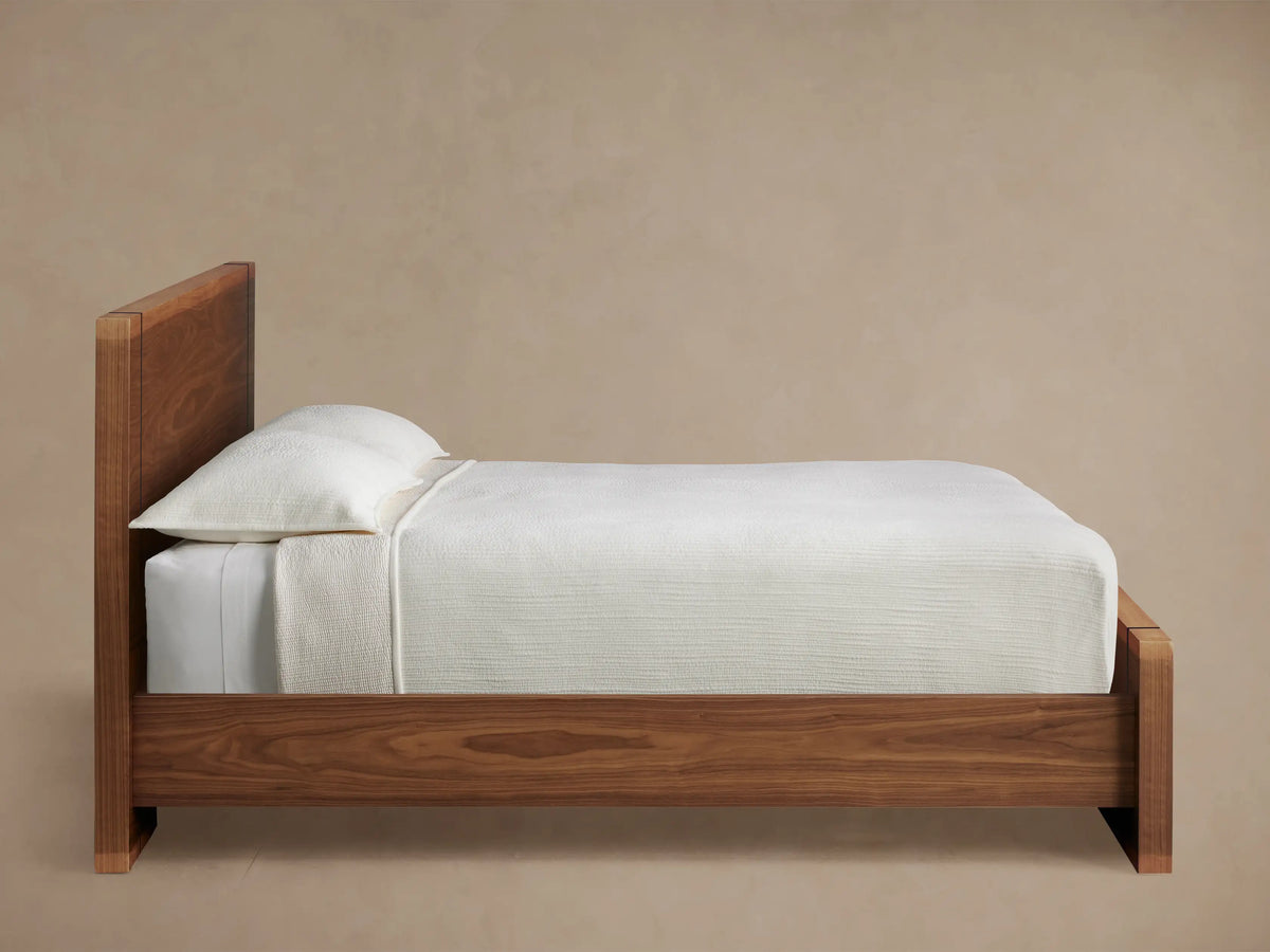 Close-up of Mihaela Bed's rich brown solid wood frame with natural grain, featuring a thin black vertical accent strip.