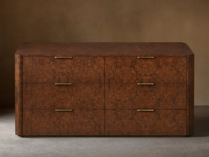 Wooden dresser with a textured, dark brown finish featuring six drawers. Each drawer has a sleek gold-toned handle. Set against a plain wall.