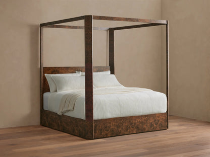 Wooden four-poster bed with white bedding and pillows, set in a minimalistic room with beige walls and hardwood flooring.