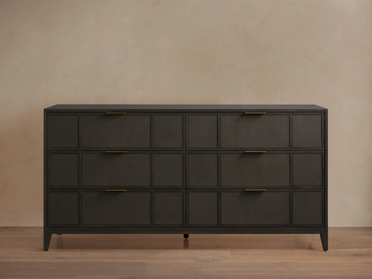 Olina Six-Drawer Dresser with dark oak finish, featuring raffia-textured front panels, six drawers, and brass pulls on wooden floor.