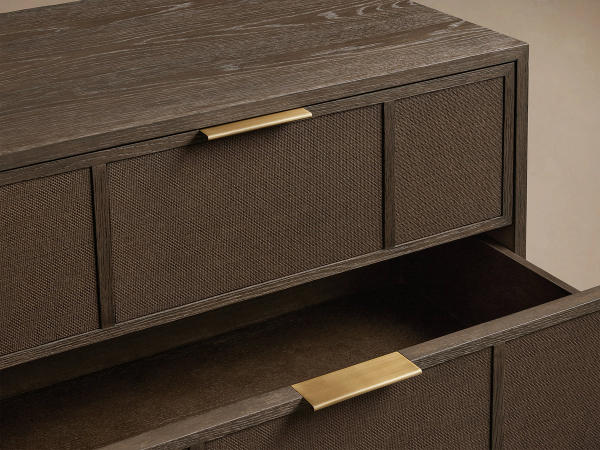 Olina Closed Nightstand: Angled view of dark oak nightstand with raffia drawer fronts, brass pulls. Bottom drawer partially open.