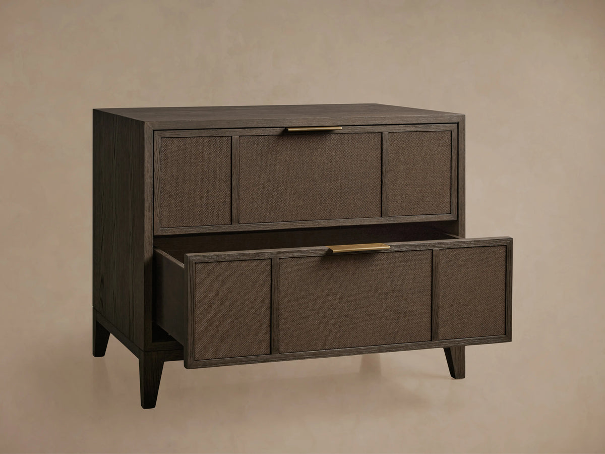 Olina Closed Nightstand, dark oak with textured raffia fronts. Top drawer closed, bottom open, revealing interior. Brass pulls.