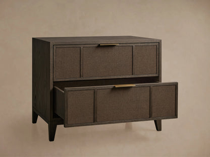 Olina Closed Nightstand, dark oak with textured raffia fronts. Top drawer closed, bottom open, revealing interior. Brass pulls.