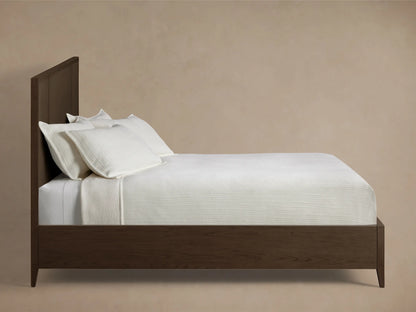 Close-up of the dark brown oak wood frame and textural raffia panel of the Olina Bed headboard.