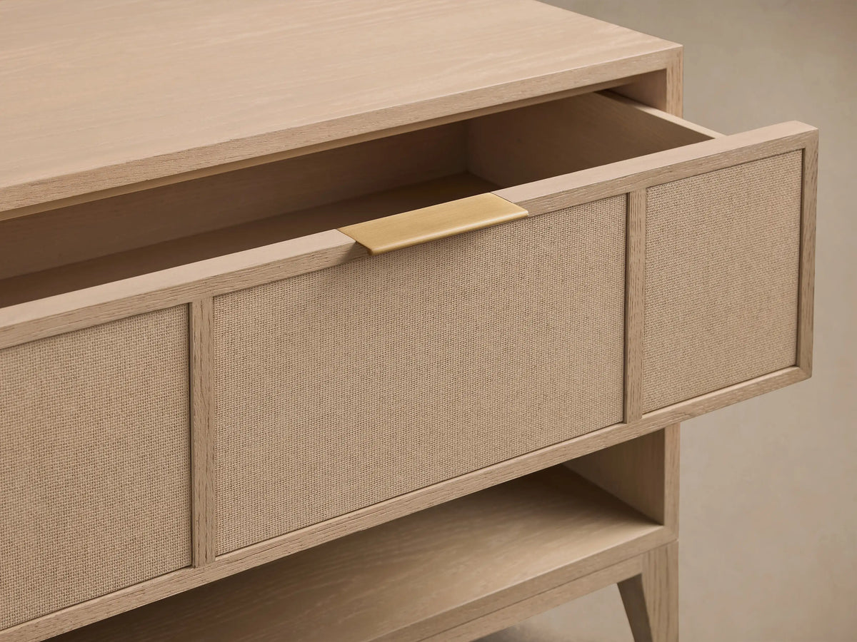 Close-up of natural oak Olina Open Nightstand with open drawer, beige raffia front, and brass pull.
