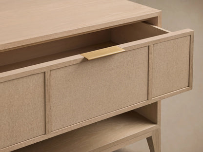 Close-up of natural oak Olina Open Nightstand with open drawer, beige raffia front, and brass pull.
