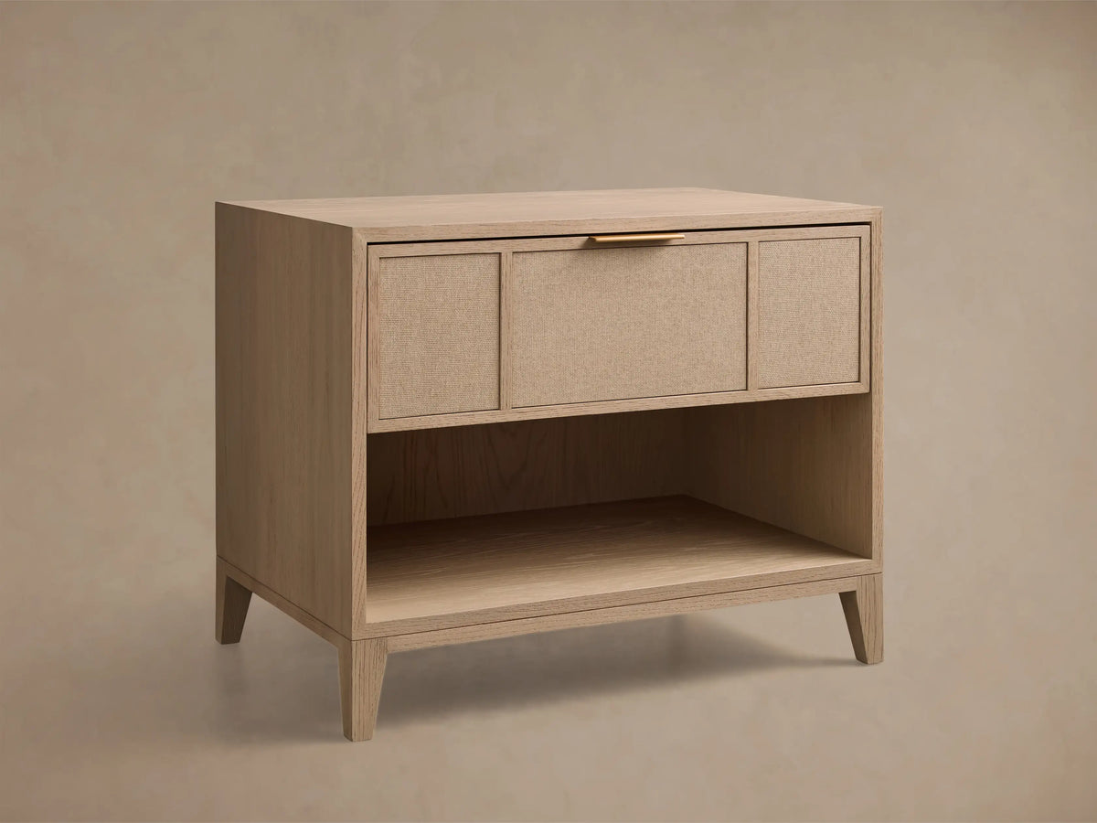 Front view of the light oak Olina Open Nightstand with a single drawer featuring textured raffia and a brass pull, and an open shelf.
