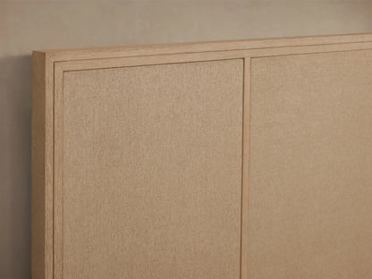 Front view of the Olina Bed with a natural oak wood frame and textural tan raffia panels. White quilted bedding.
