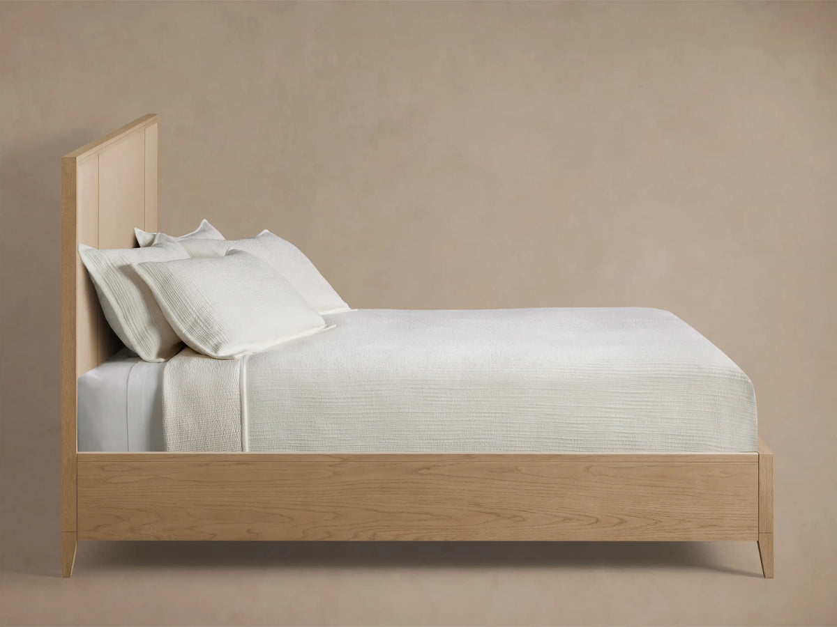 Close-up of the Olina Bed headboard, featuring light oak wood framing with textured light beige raffia panels.