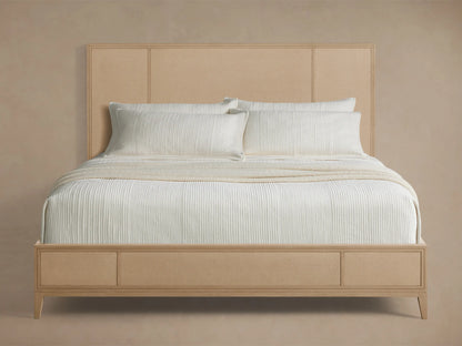 Front view of the light oak Olina Bed with framed raffia headboard and footboard, styled with white bedding.