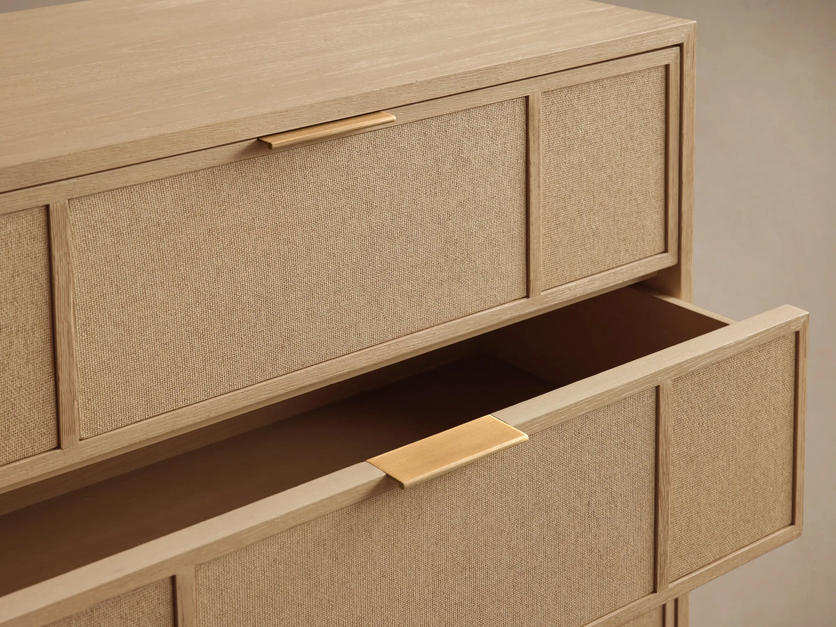 Front view of the natural oak Olina Five-Drawer Dresser, featuring five drawers with framed raffia panels and brass pulls.