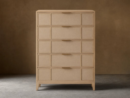 Front view of the natural oak Olina Five-Drawer Dresser, featuring five drawers with framed raffia panels and brass pulls.