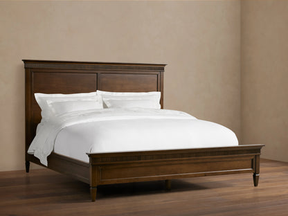 Ottavia Bed made of Tanganika wood with a dark brown finish, featuring a high headboard and white bedding on a wooden floor.