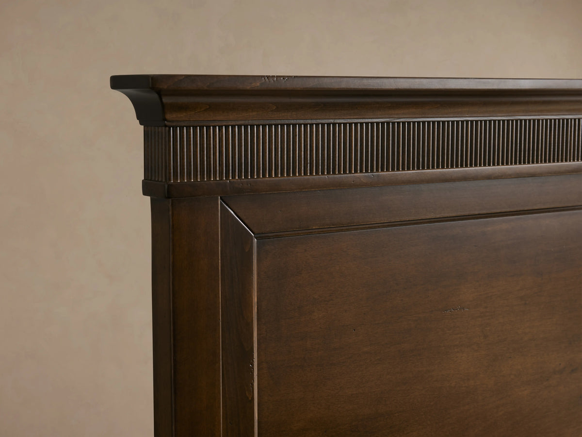 Ottavia Bed frame detail showing dark Tanganika wood with a fluted, hand-applied finish top edge on a smooth panel.