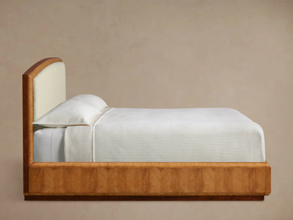 Close-up of the Palma Bed headboard, featuring dark mahogany wood trim, curved cerajeira veneer, and light cream textured fabric.