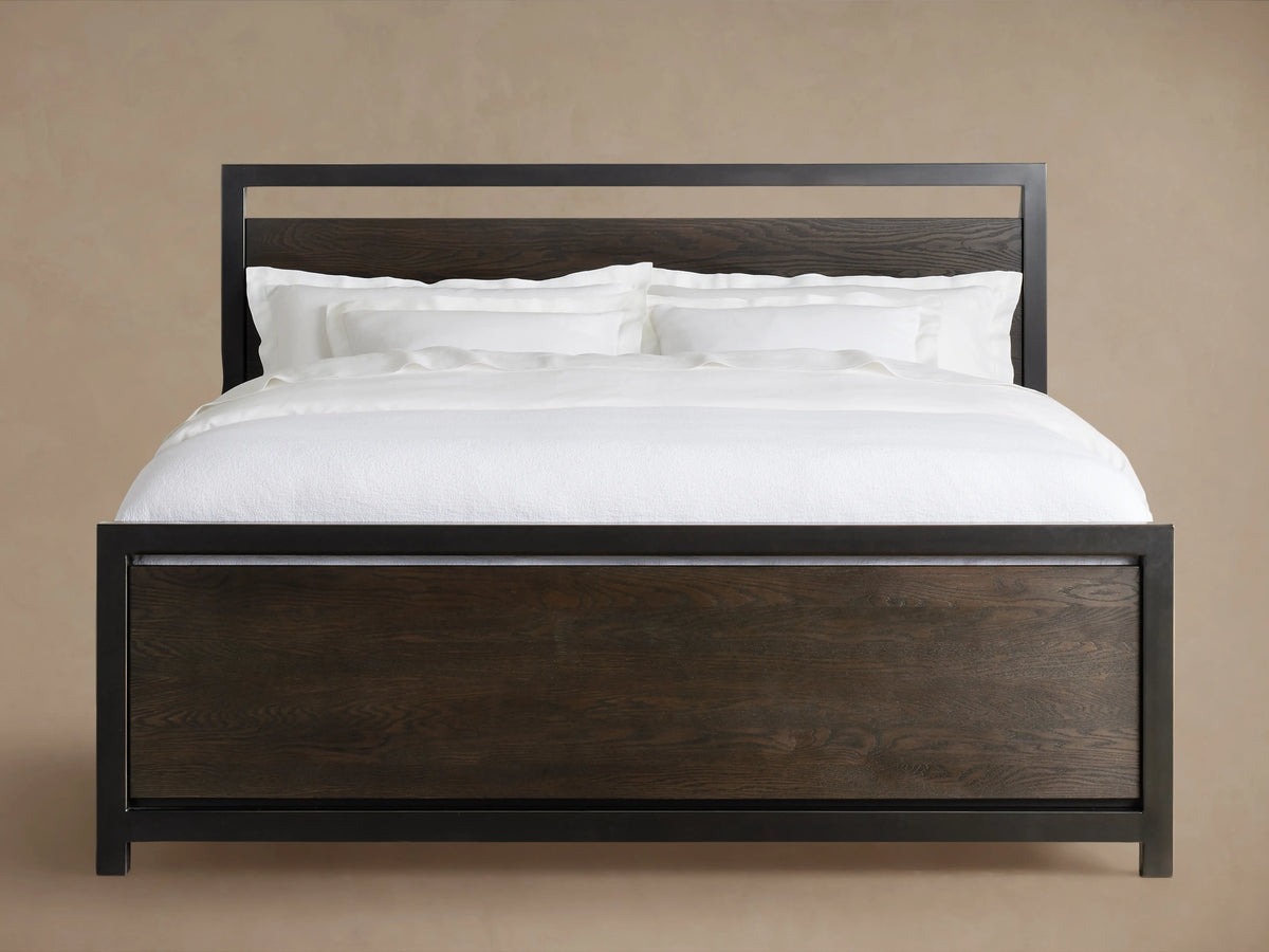 A Palmer Storage Bed with a dark wooden frame and white bedding, featuring a sleek iron headboard and footboard design.