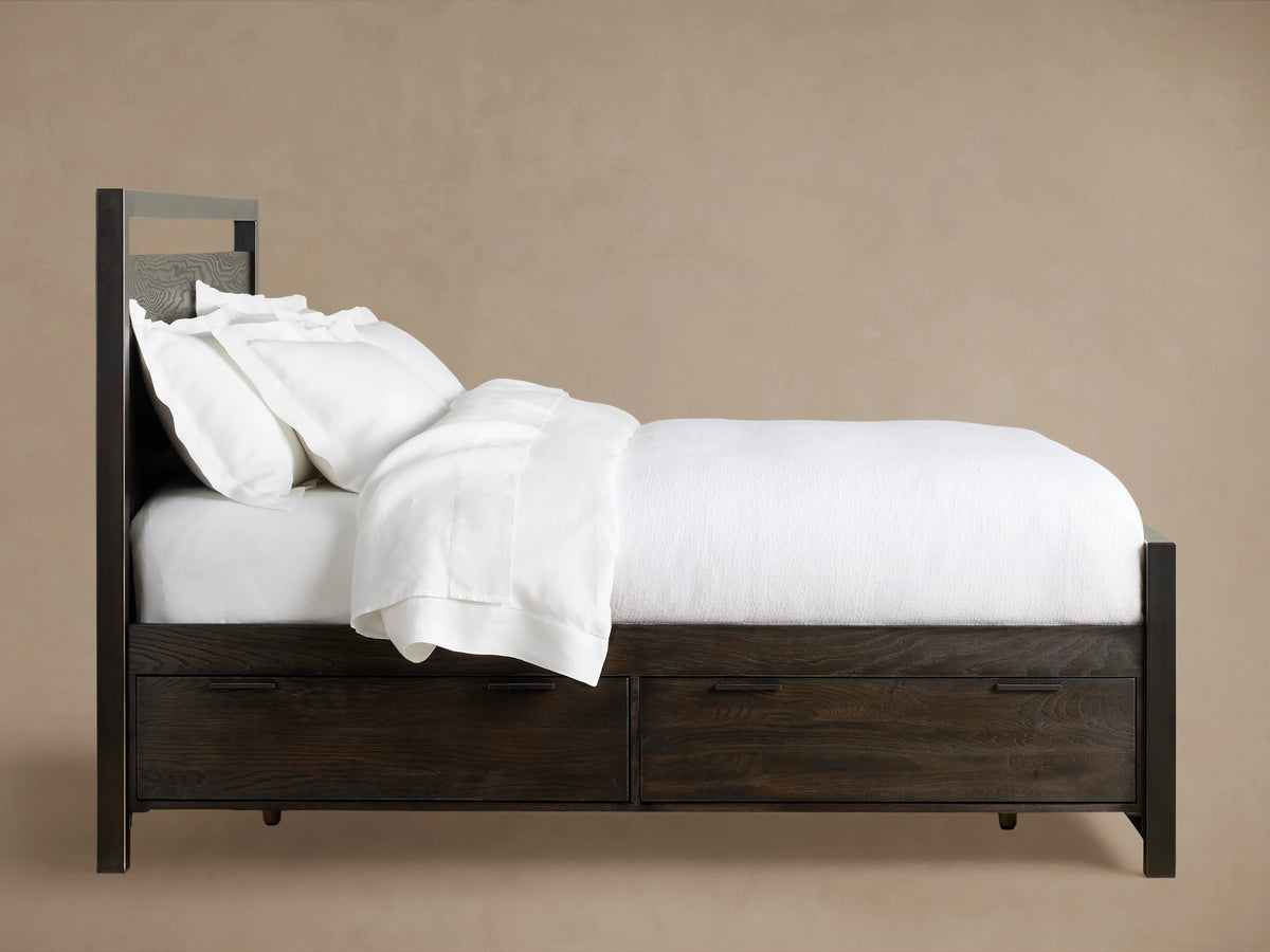 Palmer Storage Bed in a neutral room, featuring a solid wood frame with visible grain, black metal accents, and white bedding.