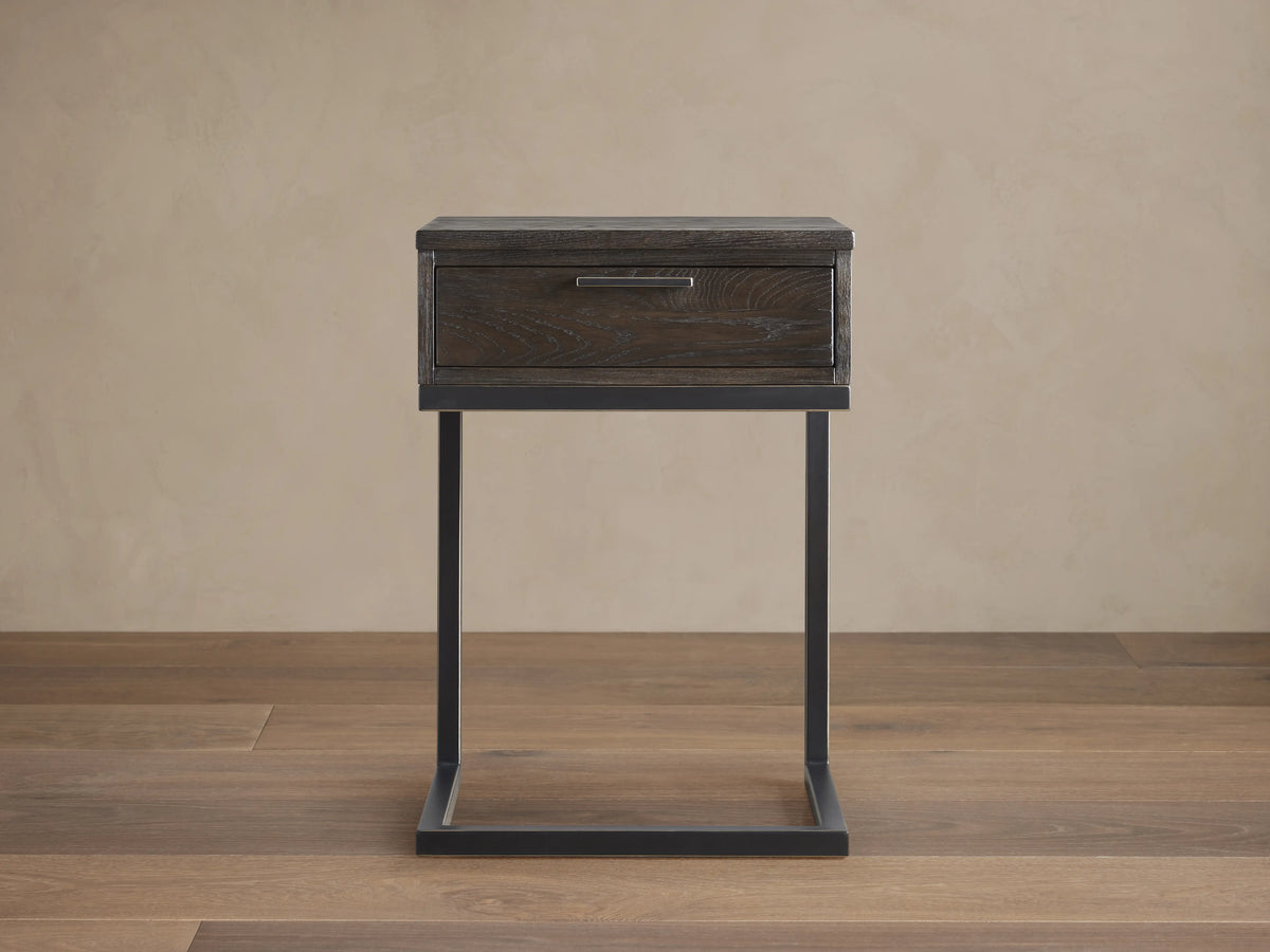 Palmer Storage Nightstand with dark wood finish, single drawer, and black metal Parsons-style frame on wooden floor.