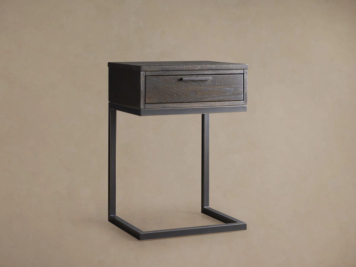 Palmer Storage Nightstand featuring a partially open drawer with visible wood grain pattern in a dark finish, metal handle, and iron frame.