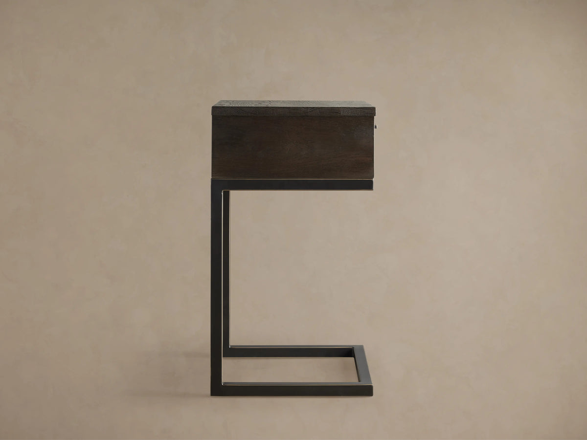 Palmer Storage Nightstand featuring a dark wooden drawer and a minimalist black iron Parsons-style frame against a beige background.