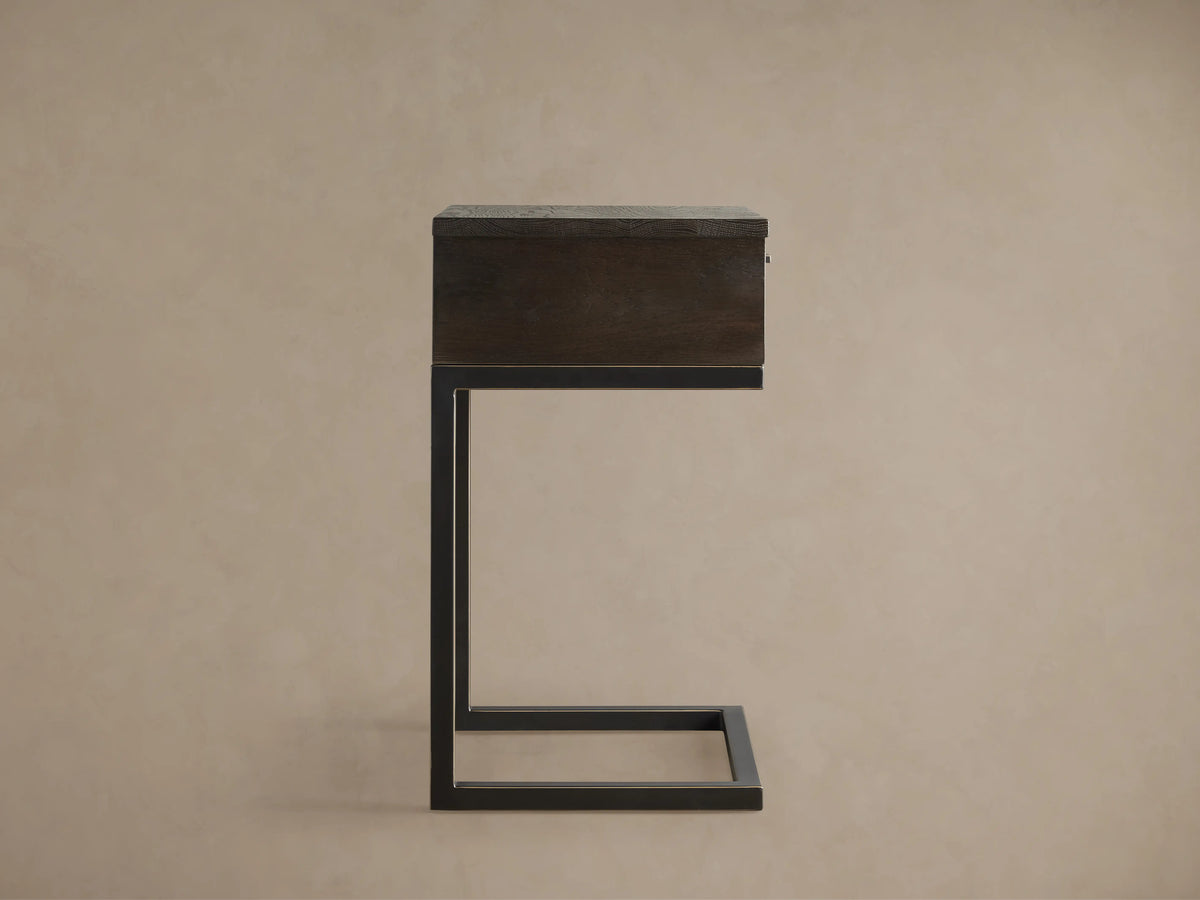 Palmer Storage Nightstand with a dark wood finish, rectangular shape, and black metal frame in a side profile view against a beige background.
