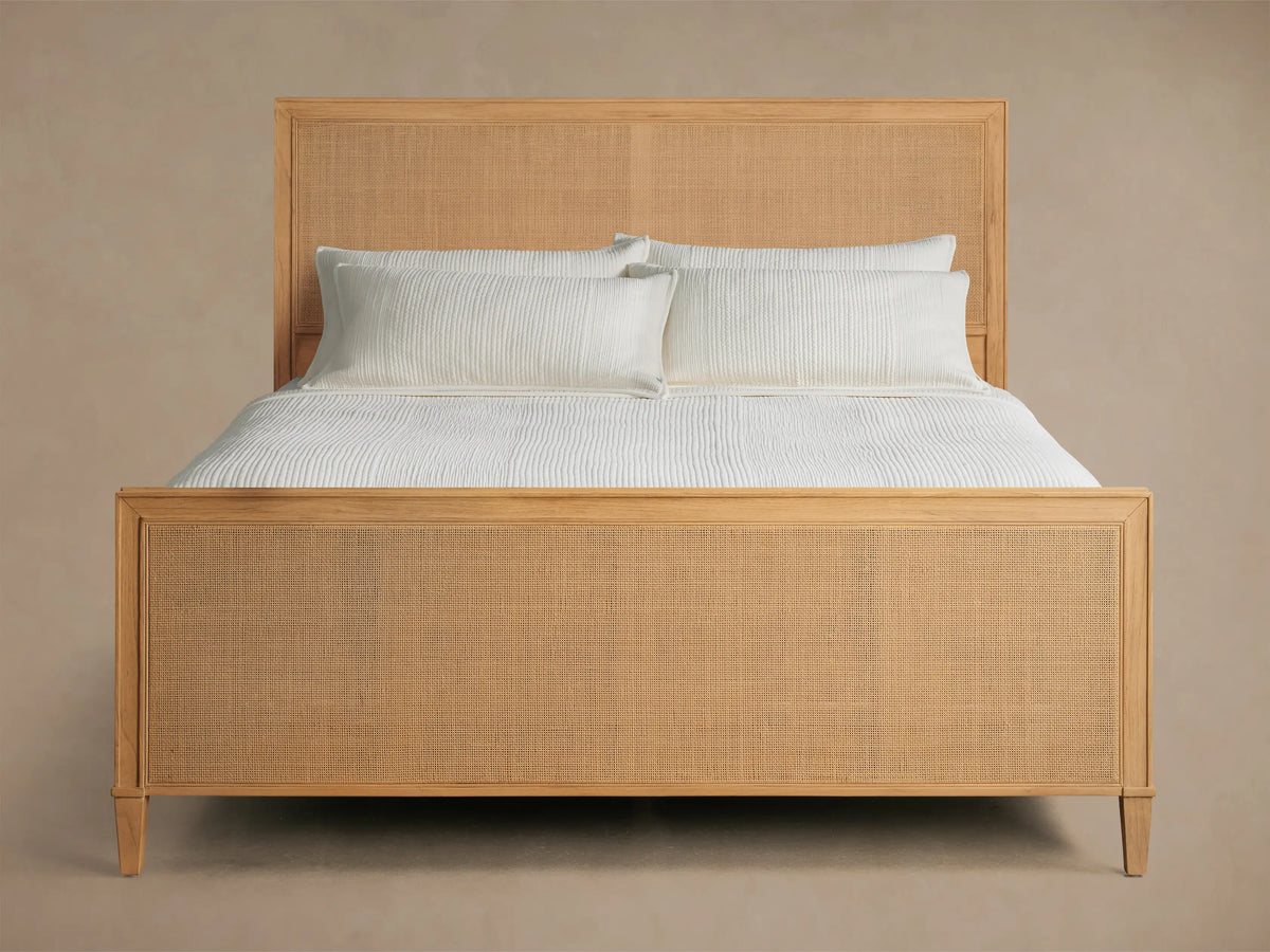 Front view of the natural wood Pearson Cane Bed, featuring a woven cane headboard and footboard, dressed with white bedding.