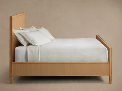 Close-up of the light natural wood frame with hand-carved molding and woven cane panel of the Pearson Cane Bed.