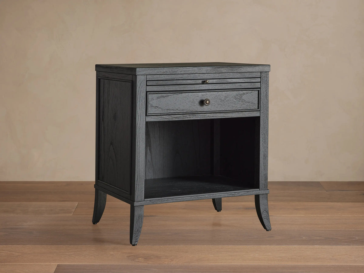 Pearson Nightstand. Black wooden nightstand with pull-out tray, drawer with molding and bronze knob, open shelf below.