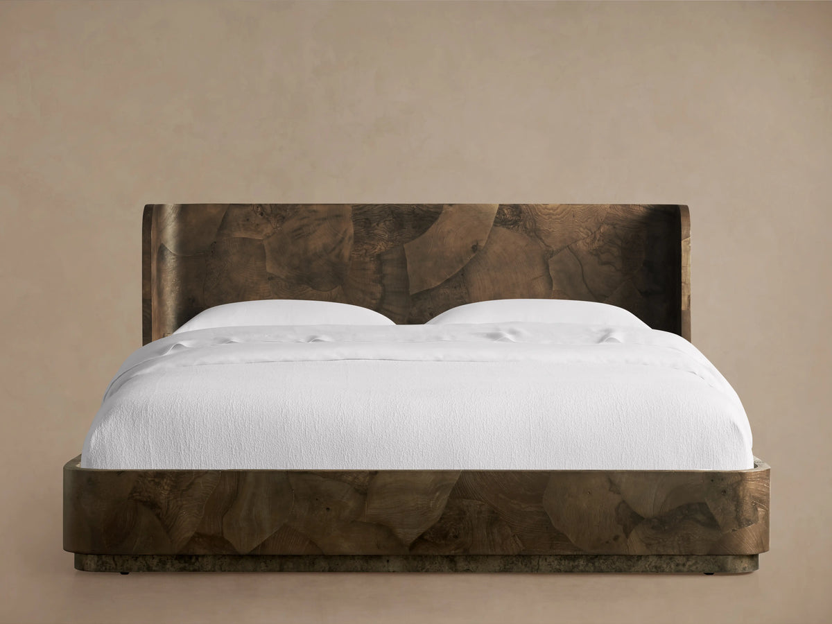 Polanco Bed with a high, wood-patterned headboard and smooth, white bedding. The wood features distinctive grain patterns.