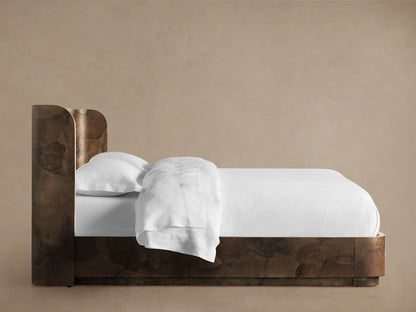 Bed made from dark wood with natural grain pattern, featuring a headboard. White bedding on a sturdy, low frame on wooden floor.