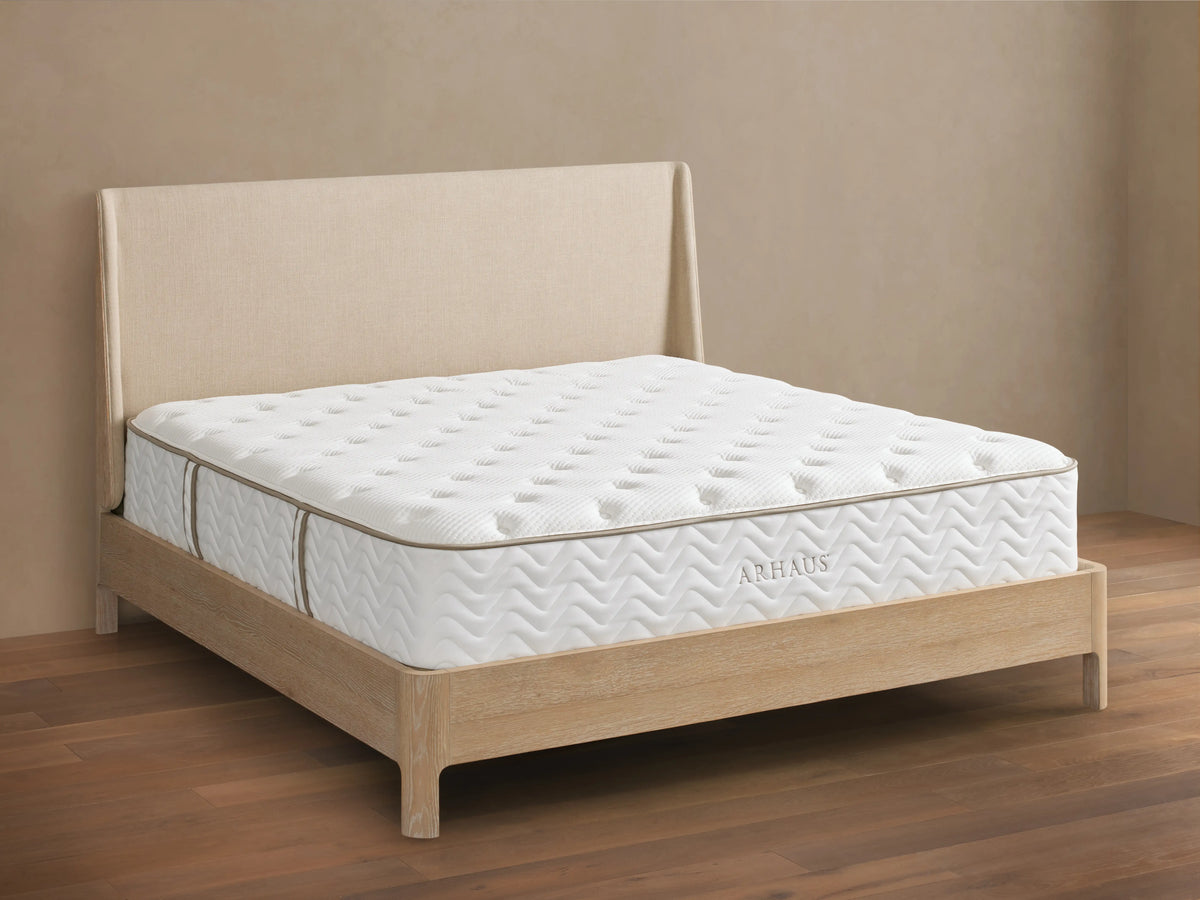 Premium Plush Mattress with soft, quilted cotton cover on wooden bed frame, beige upholstered headboard, logo visible on side.