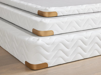 Premium 4" Platform with white quilted fabric, brass-finished metal corner guard on wood floor, emphasizes durability.