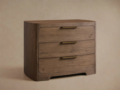 Front view of the Redding Nightstand, a medium brown wooden nightstand with rounded edges, three drawers, and brass pulls.