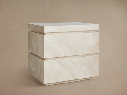 Rive Stone Nightstand, two-drawer, light beige Victoria Falls stone with natural veining, against a beige wall & wooden floor.