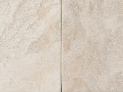 Close-up of Rive Stone Nightstand, made of polished beige Victoria Falls stone. Top drawer is partially open, revealing light wood interior.