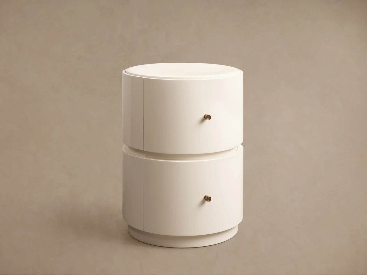 Creamy off-white Riya Round Nightstand with glossy finish, top drawer slightly open, revealing interior & brass knob.