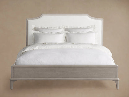 Side profile of the St. Martin Bed with a light grey weathered oak frame, white upholstered curved headboard, and white bedding.