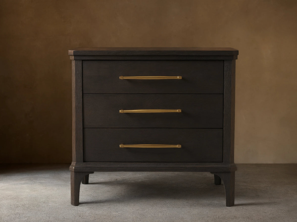 St. Martin Closed Nightstand shown in dark oak finish with three drawers. Brass-finished handles complement its craftsman design.