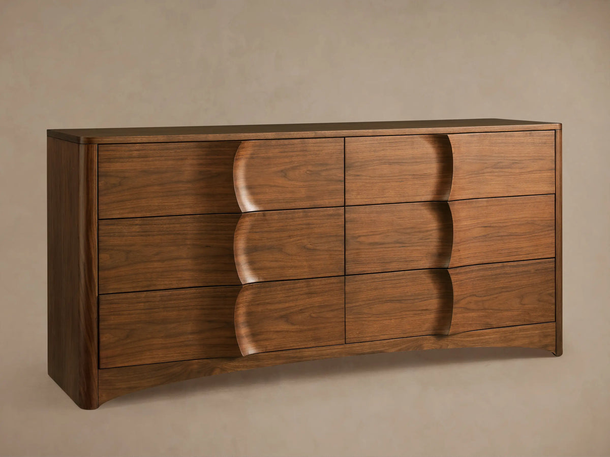 Close-up of Westyn Six-Drawer Dresser, rich brown American walnut veneer with visible grain and a partially open drawer revealing curved detailing.