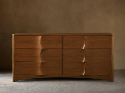Westyn Six-Drawer Dresser: Warm brown walnut wood with 6 drawers, featuring unique carved, concave wave-like fronts.