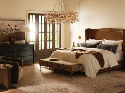 Winslet Bed with a high, curved upholstered headboard and frame in light beige, dressed with white bedding and a gray throw.