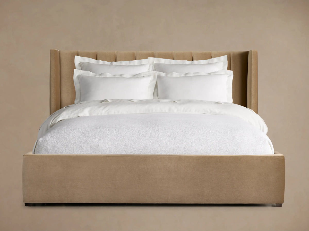 Wyller Channel-Stitched Bed with a tall, channel-stitched tan headboard, low footboard, and white bedding on a wood floor.