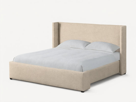 Front view of the beige upholstered Wyller Bed featuring an angled wingback headboard, made with white bedding.