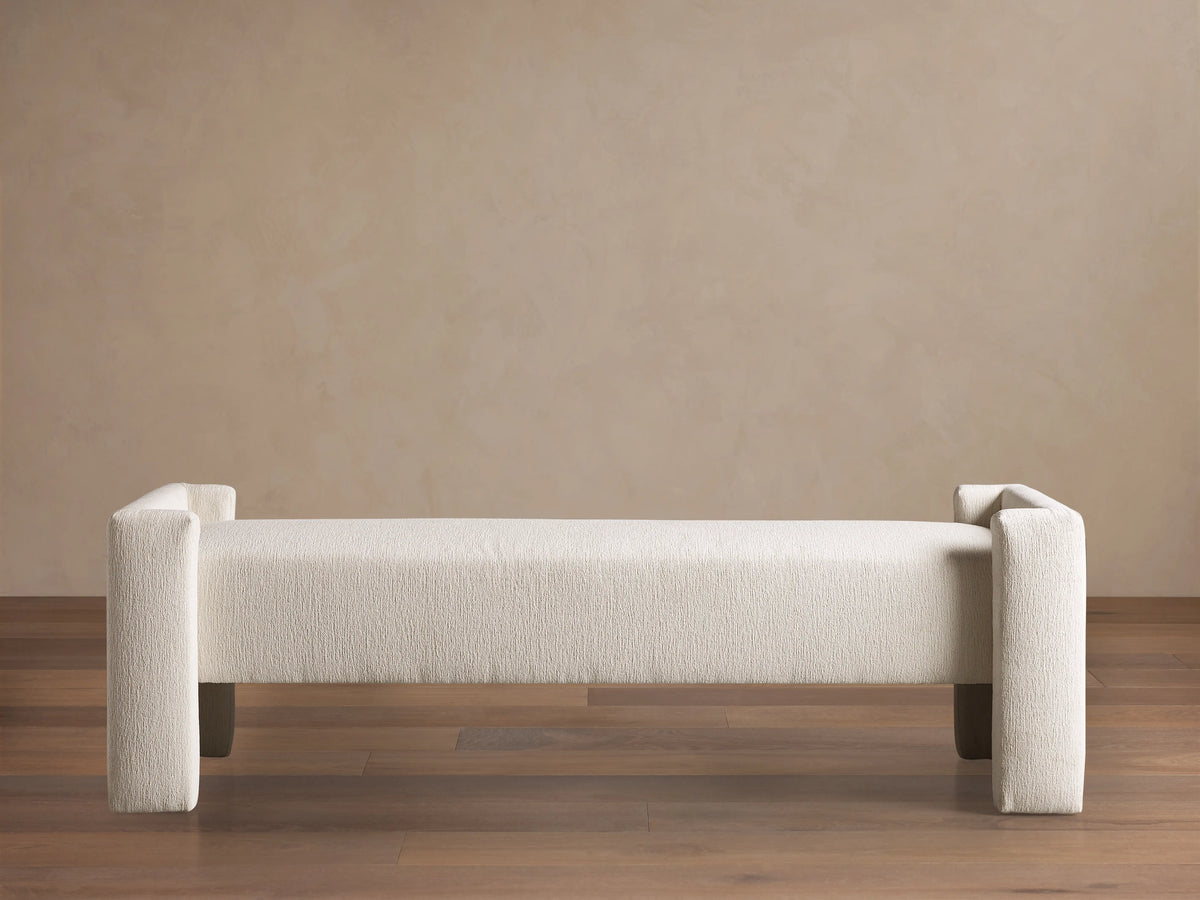 Cream Tania Cashmere Wyller Bench with thick square legs and raised ends, displayed on a wood floor.