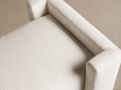 Close-up of Wyller Bench in textured Tania Cashmere off-white fabric, showing seat and armrest from a high angle.