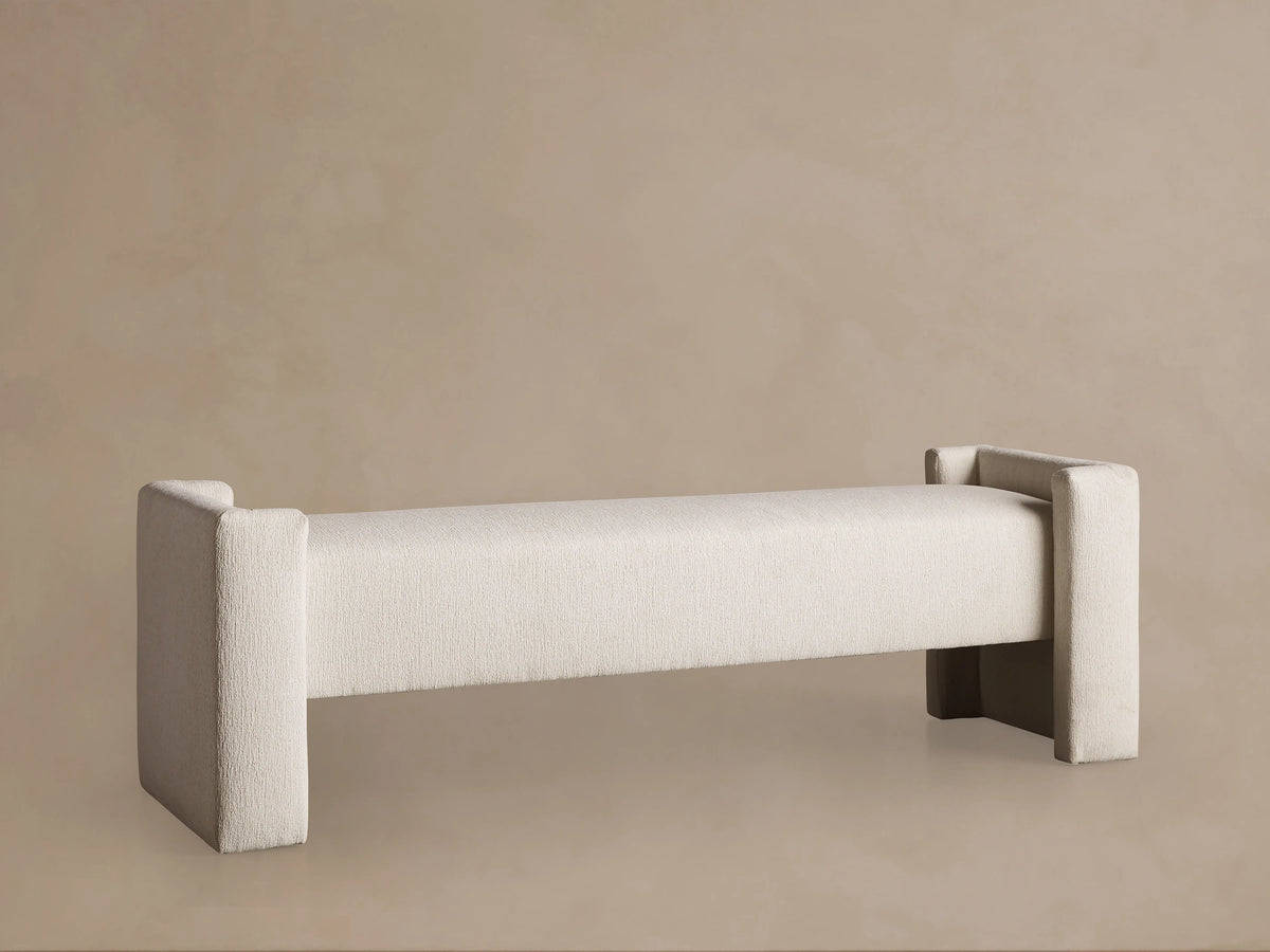 Cream Tania Cashmere Wyller Bench with thick square legs and raised ends, displayed on a wood floor.