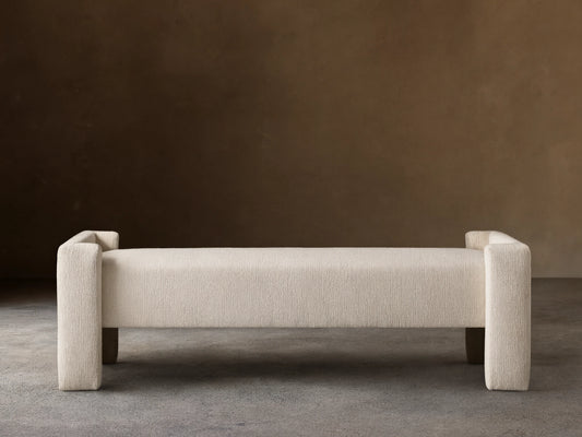 Cream Tania Cashmere Wyller Bench with thick square legs and raised ends, displayed on a wood floor.