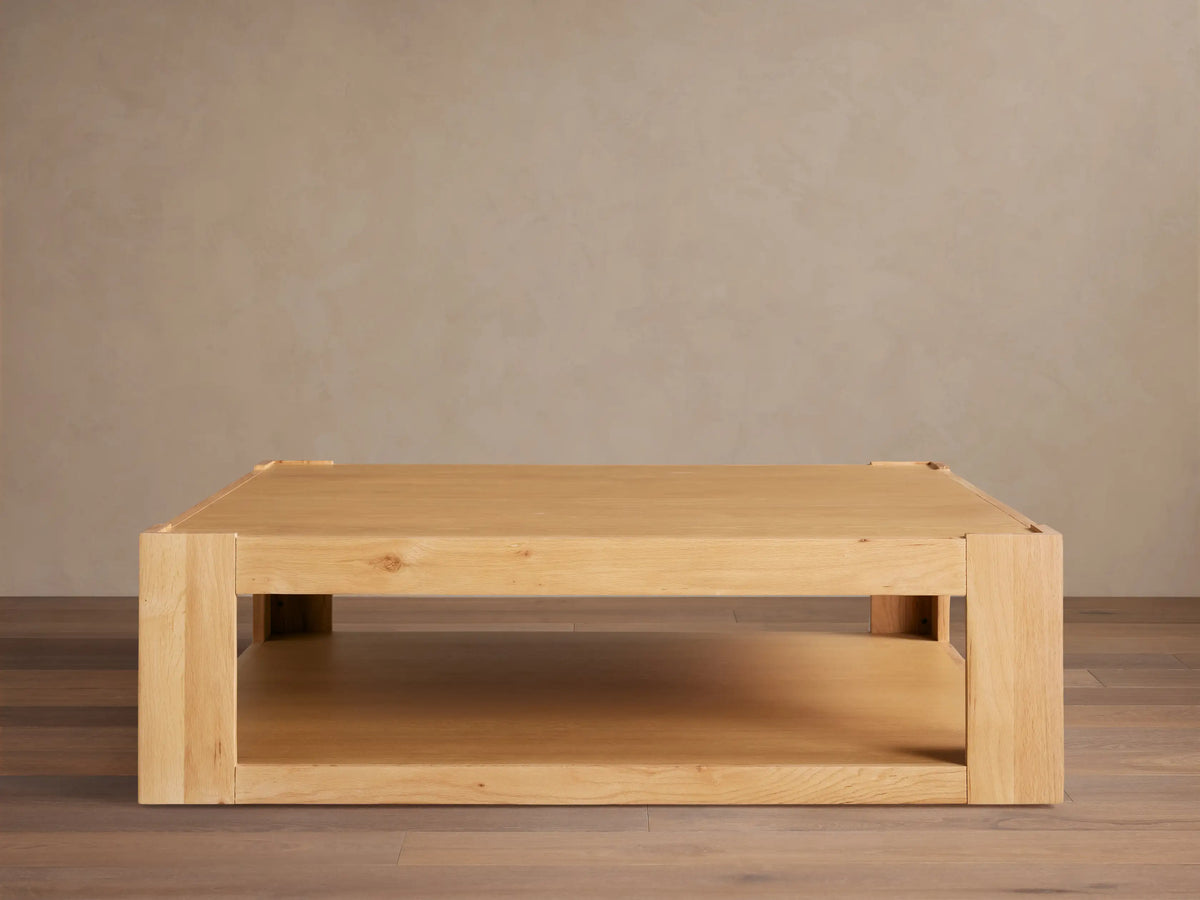 Devon Coffee Table, square natural oak wood. Features a thick top, sturdy square legs, and a practical lower storage shelf.